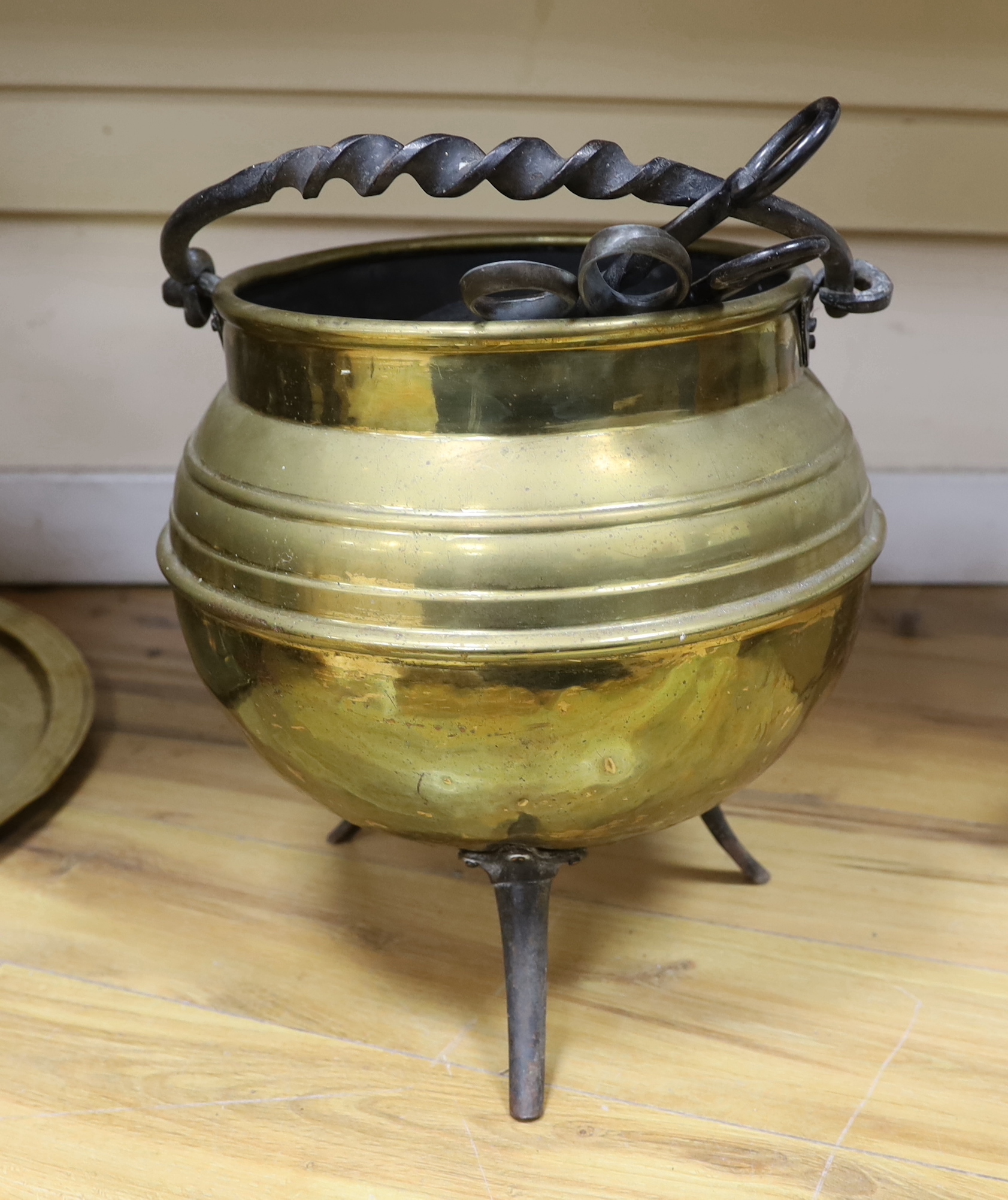 A brass cauldron shaped coal scuttle, a large circular tray, two kettles, a jug and a vase, tray 65cm diameter